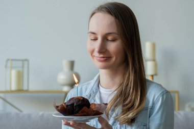 Güzel bir kadın doğum günü pastasında mum üflüyor.