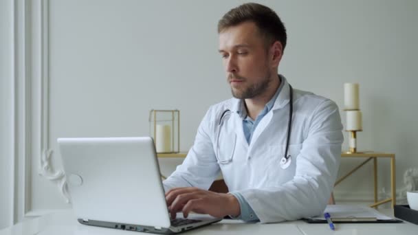 Doctor using laptop in medical office. Man is working with documents and laptop in his medical office — Stock Video