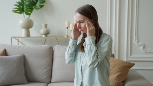 Unglückliche Frau leidet zu Hause unter Kopfschmerzen, wenn sie auf der Couch sitzt — Stockvideo