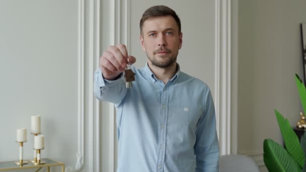 Mężczyzna pokazuje klucze do swojego nowego mieszkania w salonie. — Wideo stockowe