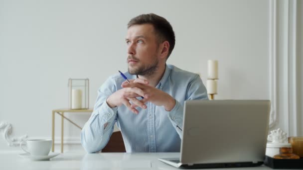 Homem senta-se em casa mesa de escritório com laptop pensando em inspiração solução problema de pesquisa ideias perdidas em pensamentos. — Vídeo de Stock