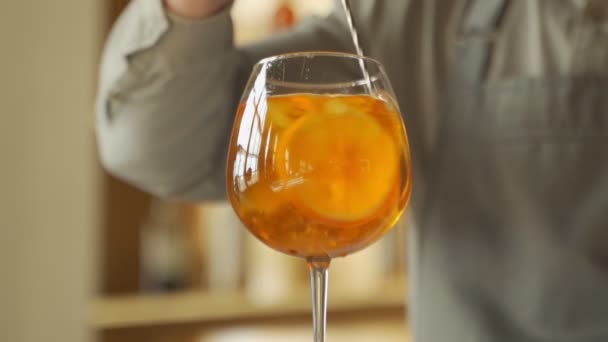 特写酒保准备了一只鸡尾酒手，用勺子在吧台上搅拌橙色的夏季鸡尾酒. — 图库视频影像
