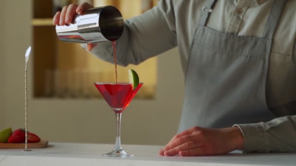 Бармен наливает коктейль Cosmopolitan в бокал мартини — стоковое видео