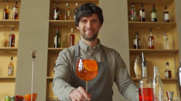 Barman dává koktejly klientům. Stojí u pultu v baru. Muž se dívá na kameru. — Stock video