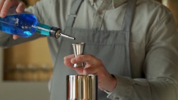 Närbild man bartender häller blå curacao dryck från jigger i shaker. — Stockvideo