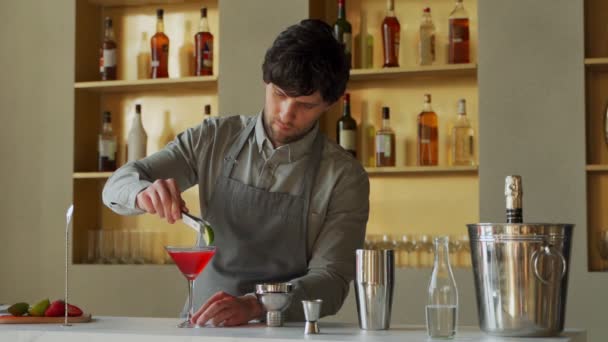 O barman prepara um coquetel cosmopolita, decora o coquetel com limão — Vídeo de Stock