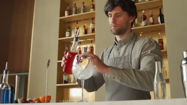 El camarero prepara una mano de cóctel revolviendo un cóctel naranja de verano con una cuchara en el mostrador del bar. — Vídeos de Stock