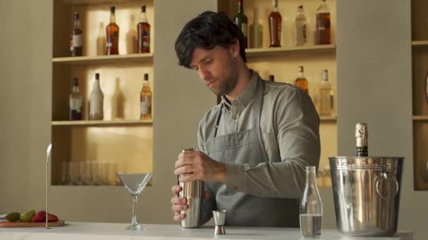 Бармен наливает коктейль Cosmopolitan в бокал мартини, украшает коктейль лаймом — стоковое видео