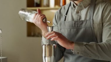 Yakın plan profesyonel barmen, modern modaya uygun bir barda klasik bir kokteyl yaparak bir bardağa rom dolduruyor..