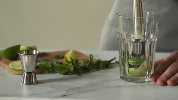 Il barista prepara un cocktail mojito usando il madler. Barista schiaccia menta e lime con un madler — Video Stock