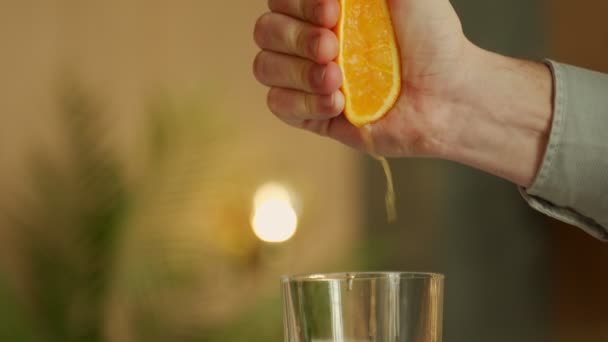 En ung mans hand pressar juice från en apelsin till ett glas. — Stockvideo