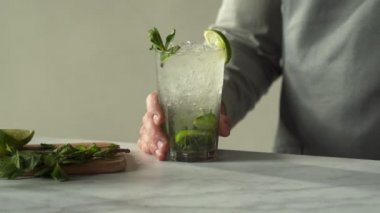 Barmen bar tezgahında kokteyl hazırlıyor ve hazırlıyor. Lokanta barında mojito kokteyli servis ediliyor.