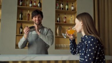 Barmen, barda kokteyl hazırlarken kadın müşterisiyle konuşuyor. 