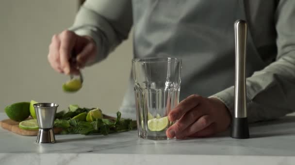 Il barista prepara un cocktail mojito usando il madler. Barista schiaccia menta e lime con un madler — Video Stock