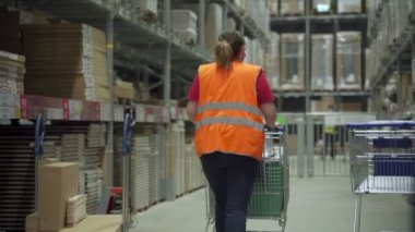 Kadın işçi depoya bir araba dolusu mal sokuyor.