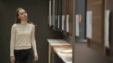 Mağazadaki genç kadın mutfak mobilyaları için malzeme seçiyor..