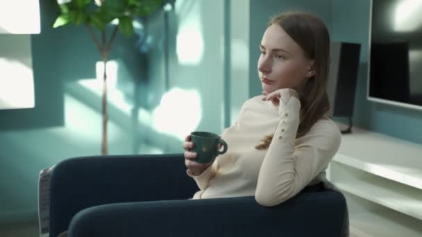 Mujer en casa sentada en silla, relajada bebiendo café o té — Vídeos de Stock