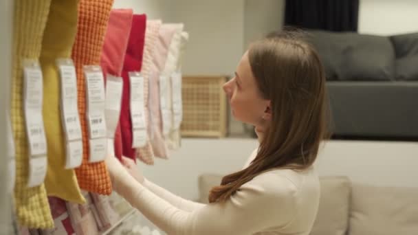 Morena escolhe um travesseiro na prateleira da loja — Vídeo de Stock