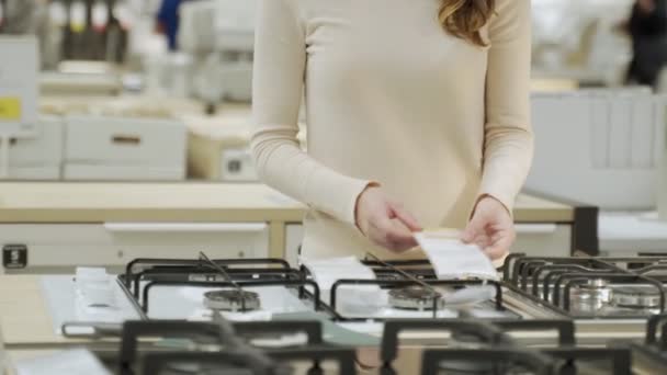 家電店で新しいガスストーブを選ぶ女性 — ストック動画