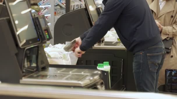 Close-up kobieta za pomocą self checkout maszyny w supermarkecie, wykrawa produkty w kasie — Wideo stockowe