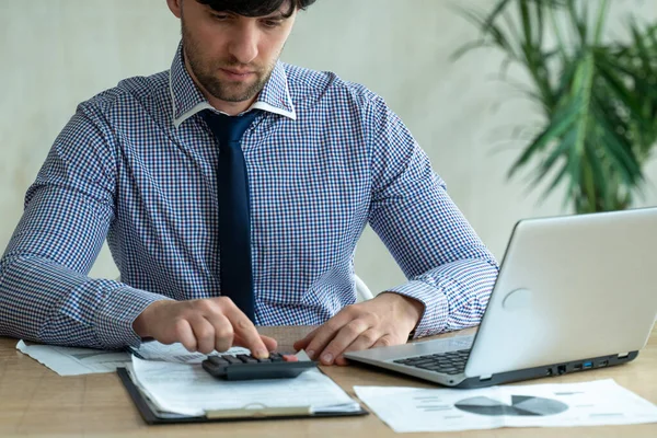 Бизнесмен использует калькулятор на рабочем столе с ноутбуком. Удаленная работа, технологии и концепция людей — стоковое фото