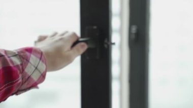 Bir kadının eli mutfaktaki siyah pencereyi kapatır.