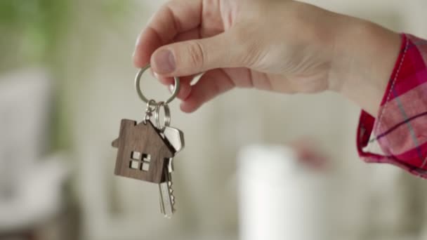 女性は家の修理を背景に男の手の中の新しい家に鍵を渡します。不動産の売却の概念 — ストック動画