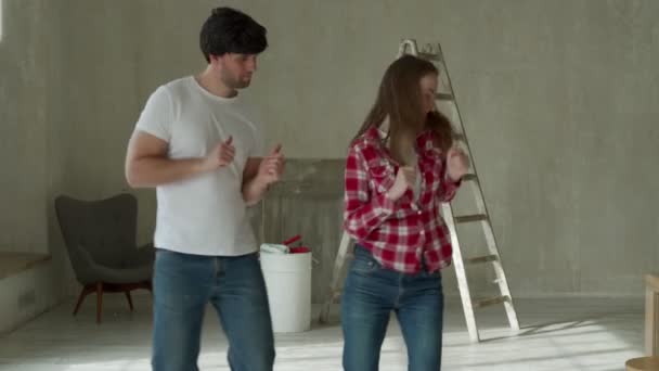 Jeune couple réparation de la maison chanter et danser. Redécoration d'appartements et construction de maisons lors de la rénovation et l'amélioration. — Video