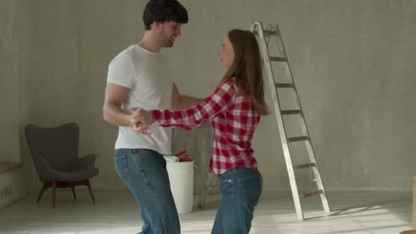 Jeune couple réparation de la maison chanter et danser. Redécoration d'appartements et construction de maisons lors de la rénovation et l'amélioration. — Video