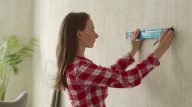 İnşaat seviyesini kullanan genç bir kadın. Bir kadın evde tamirat yapıyor.