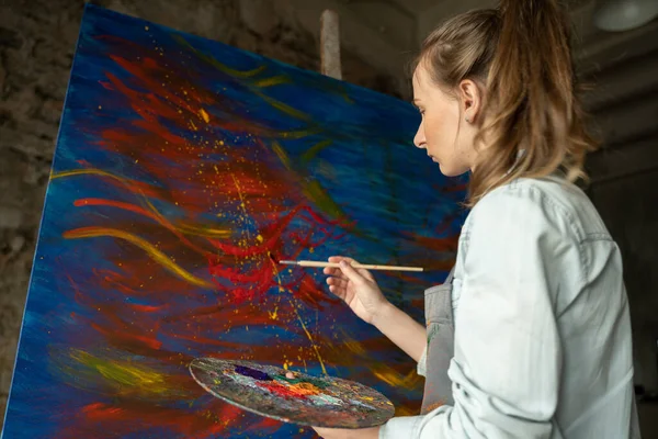 Artista donna davanti a un cavalletto, dipingere con un pennello, utilizzando olio o vernice acrilica — Foto Stock