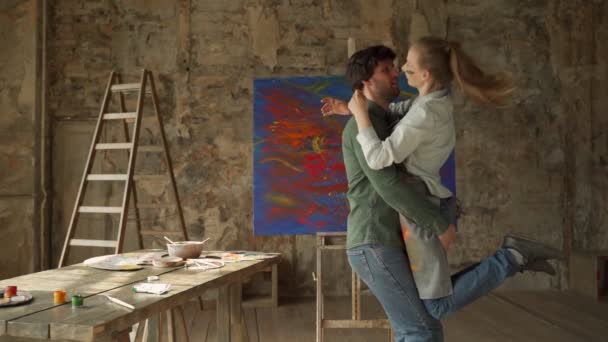 Pareja joven de artistas abrazan contra el fondo de un cuadro pintado — Vídeo de stock