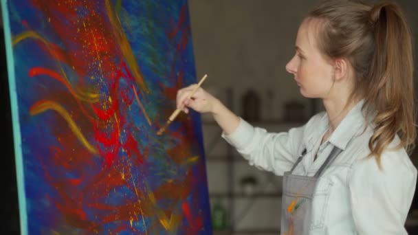 Γυναίκα καλλιτέχνης μπροστά από ένα καβαλέτο, ζωγραφική με ένα πινέλο, χρησιμοποιώντας λάδι ή ακρυλικό χρώμα — Αρχείο Βίντεο