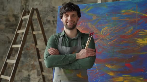 Portrait d'un jeune artiste masculin dans son atelier. Homme artiste a les bras croisés et regarde la caméra — Video