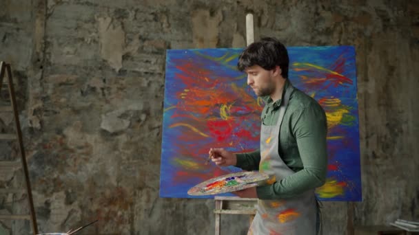 男人是个艺术家，拿着画笔，画着一幅抽象的图画 — 图库视频影像