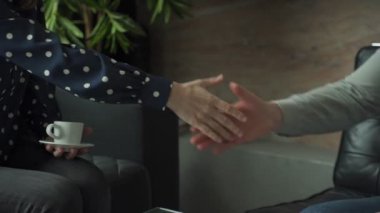 İş adamlarının el sıkışması. Ofiste kanepede otururken bir erkek ve bir kadın el sıkışıyor.