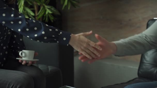 Zbliżenie biznesmenów ściskających dłonie. Mężczyzna i kobieta podają sobie ręce siedząc na kanapie w biurze — Wideo stockowe