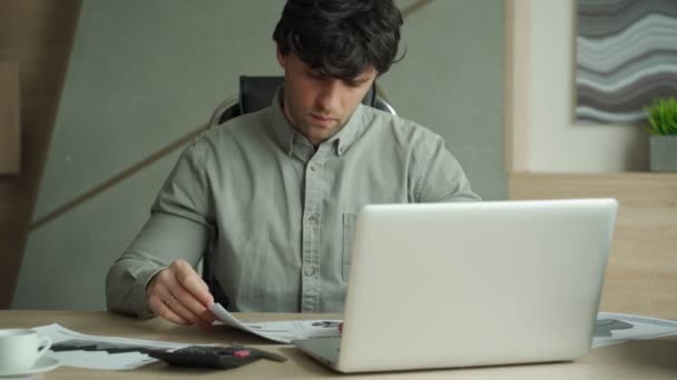 Um homem frustrado sentado no seu local de trabalho. Jovem exausto com laptop no escritório — Vídeo de Stock
