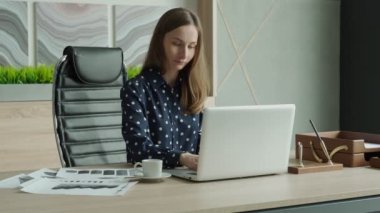 Kadın ofiste dizüstü bilgisayarla çalışıyor. Yüzünde ifade şaşkınlığı ve iş başarısı var.