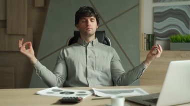 Ofiste meditasyon yapan bir adam stresle başa çıkıyor. Modern bir ofiste yoga yapan bir işletme yöneticisi.