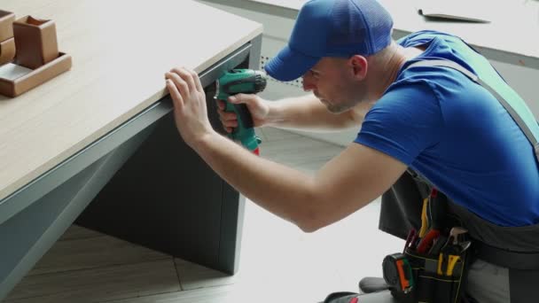 Homme bricoleur à l'aide d'un outil de tournevis électrique dans sa main et la réparation d'une table en bois — Video