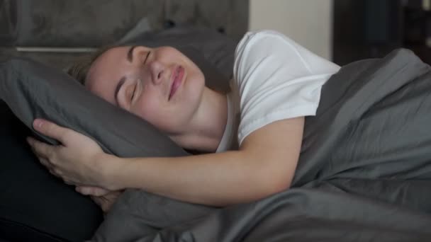 Relaxed woman in the bedroom, has pleasant dreams, keeps her eyes closed, enjoys a good rest at home — Stock Video