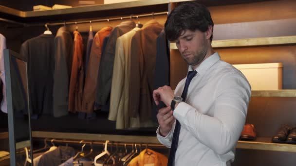 Homem de camisa abotoa o relógio de pulso no camarim — Vídeo de Stock
