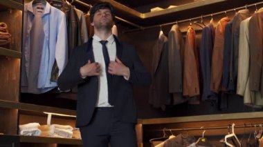 Yakışıklı bir adam soyunma odasında ceket giyer.