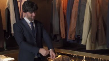 Yakışıklı bir adam soyunma odasında ceket giyer.