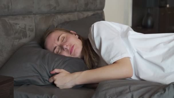 Jeune femme à la maison dans la chambre, couchée au lit, incapable de dormir en raison d'un oreiller inconfortable, souffrant d'insomnie — Video