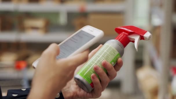 Close-up vrouw in een medisch masker kiest voor agrarische chemicaliën voor bloemen en planten met behulp van een smartphone — Stockvideo