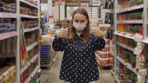 Woman wearing a protective mask shows the thumbs up in a hardware store — Stock Video