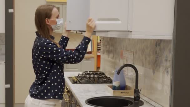 Mulher em uma máscara protetora escolhe móveis de cozinha em uma loja — Vídeo de Stock