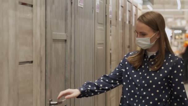 Frau mit Schutzmaske kauft im Geschäft eine Holztür für ein neues Haus — Stockvideo
